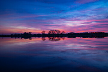 Naklejka na ściany i meble Colorful clouds after sunset and reflection in the water
