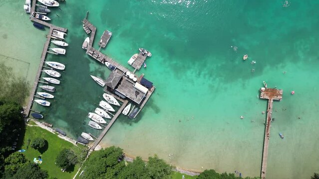 Aerial slow motion of Attersee lake and a dock with boats around it in Austria