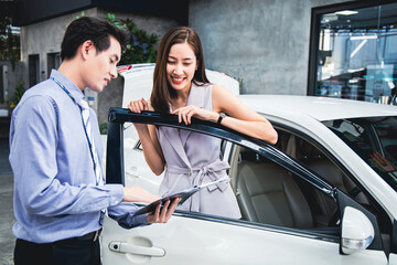 Beautiful Asian customer brought the car to check the condition of the car at the garage male employee giving details to female customers.