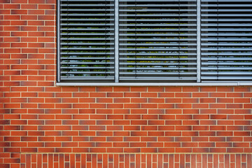 Fragment of a rectangular window with gray curtains against a red brick wall. From the Window of the World series.