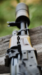 Kalashnikov assault rifle with a silencer lies on a wooden surface