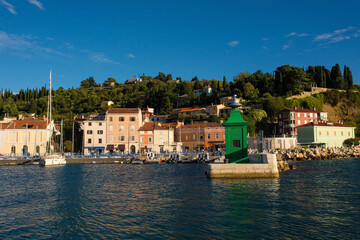 Fototapeta na wymiar A small green lighthouse on the waterfront of the historic medieval town of Piran on the coast of Slovenia 