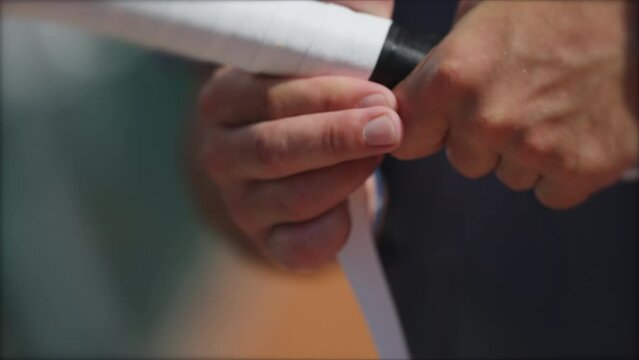 Player changing racquet tennis grip. Person replacing overgrip closeup hand renewing sport equipment