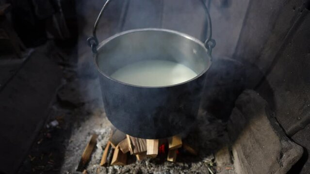 Making organic sheep cheese in wooden mountain Carpathian cheese factory with a boiling smoked cauldron with milk on open fire, Western Ukraine, Europe