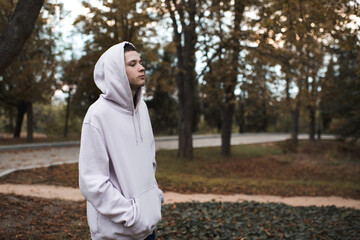 Young depressed teenager boy 22-24 year old wear hoodie with hood in dark over nature background...
