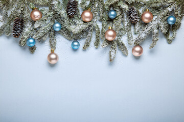 Christmas border with fir branches and decorations in pastel colors sprinkled with snow. Elegant Christmas border made up of fir branches, beige and blue balls in muted colors
