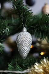 Closeup of a green Christmas tree with gold, white and silver ornaments, golden tinsel plus small decorative lights. Grey background. Joyful and happy holiday season color image. Merry xmas!