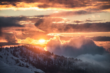 The sun is descending over the horizon covered withlow altitude clouds, Northern Italy