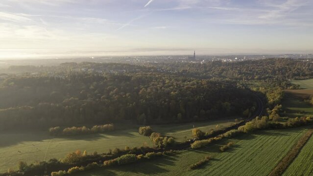 Aerial time lapse shot of city of Ulm and Ulm minster behind colorful forest on a sunny morning with some mist and nice sky