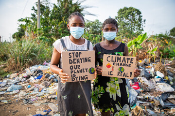 Young african girls holding signs written: stop denying our planet is dying