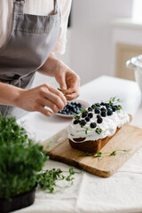 A woman confectioner decorates a delicious cupcake with berries in the kitchen. High quality photo