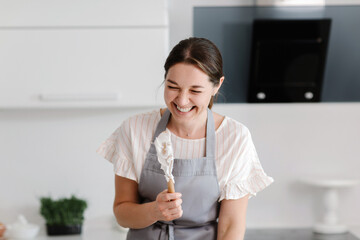 Woman confectioner prepares meringue in the kitchen. spoon with meringue. High quality photo