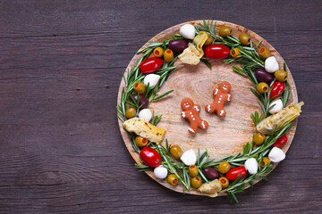 Christmas wreath appetizer board. Overhead view against a dark wood background.