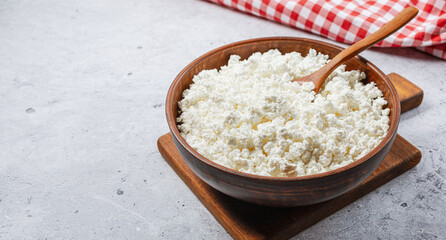 Cottage curd cheese in a wooden bowl on wooden table.