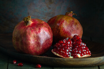 pomegranate seeds fruit Fresh ripe wooden  background open dark vintage background still life organic Red vitamins wooden plate table closeup sweet.