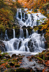 Fototapeta na wymiar Beautiful waterfall in autumn forest in Jonkoping, Sweden. Long exposure. Selective focus.