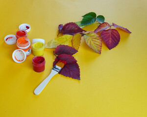 multi-colored paints in jars, red, yellow, green for coloring autumn leaves.