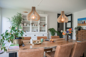 Bouquet in vase on the wooden table at modern kitchen with a lot of plants and decor elements