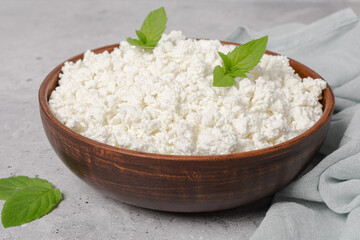 Cottage curd cheese in a wooden bowl on grey table.