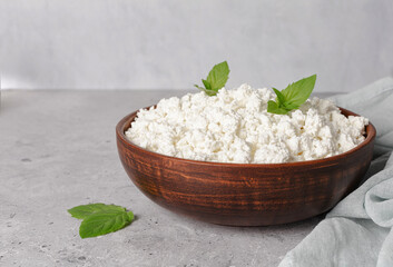 Cottage curd cheese in a wooden bowl on grey table.