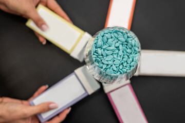 Warm wax in colored cartridges for depilation and granulated wax in a glass stand on a table.