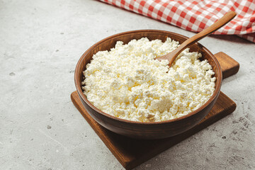 Cottage curd cheese in a wooden bowl on grey table.