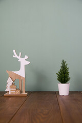 Wooden statuette in the form of a deer and christmas tree on green background. Christmas concept.