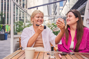 Two body positive best friends preparing for the walking while sitting at the street cafe