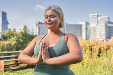 Waist up portrait view of the blonde woman meditating with prayer gesture in the nature