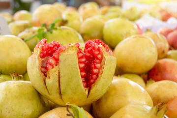 Pomegranate fruits broken into slices with inner red juicy seeds.