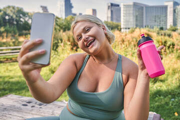 Portrait view of the full figured woman taking photo at the mobile phone