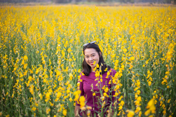 Fototapeta premium Young woman in a field of yellow flowers