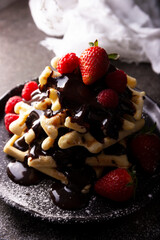 Fresh Homemade soft waffles with fruit and icing sugar covered with lots of melted chocolate.