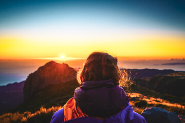 Sitting woman watching the sunrise over the beautiful mountain landscape of Pico do Ariero. Pico do...