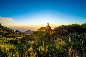 Woman walking thorugh beautiful mountain landscape of Pico do Ariero during sunrise. Pico do...