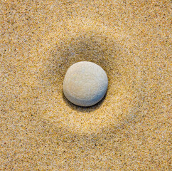 Fototapeta na wymiar Grey round stone at center of circle of sand. Zen garden. Top view.