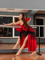 Girl in red dress are training in dance studio
