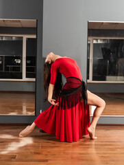 Girl in red dress are training in dance studio
