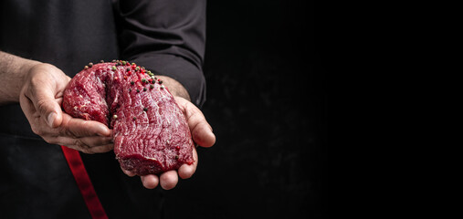 male hands holding beef meat on a dark background, Whole piece of tenderloin with steaks and spices...