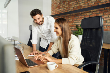 Fototapeta premium Two businesspeople talking at office using laptop