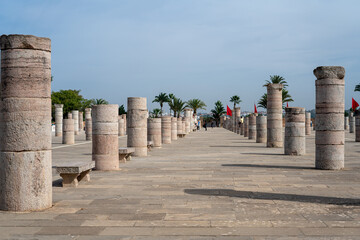 People walking around the medieval columns next to the Hassan tower in Rabat, Morocco