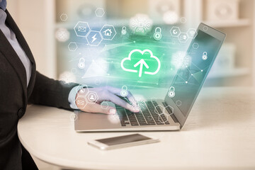 Hands working on laptop with digital icons