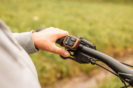 Woman hands with electric bike handlebar driving on an asphalt road in nature