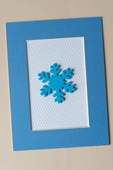blue foam snowflake ornament on textured paper with dot pattern and frame with a blue picture mat