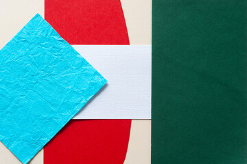 blue, red, white, and green paper shapes on beige