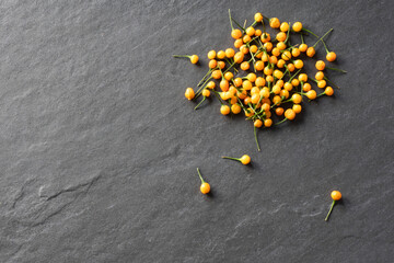 A group of yellow heirloom aji charapita peruvian peppers against a gray slate background - obrazy, fototapety, plakaty