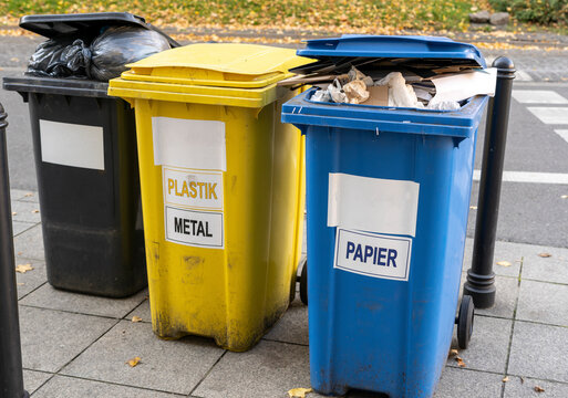 Black, blue, yellow, green garbage recycling bins on street in city. Separate waste, preserve the environment concept. Segregate waste, sorting garbage. Colored trash cans with paper, glass, plastic