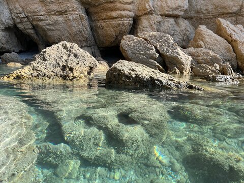 Rocky coast of Mediterranean coast with stones in transparent water.