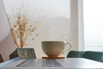 Digital laptop and coffee cup on the home desk. Time for coffee break