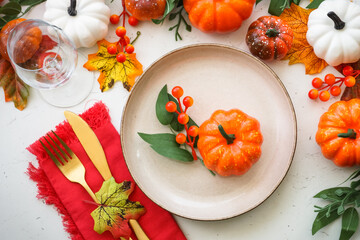 Autumn table setting. Craft plate, golden cutlery and fall decorations with pumpkins. Flat lay...